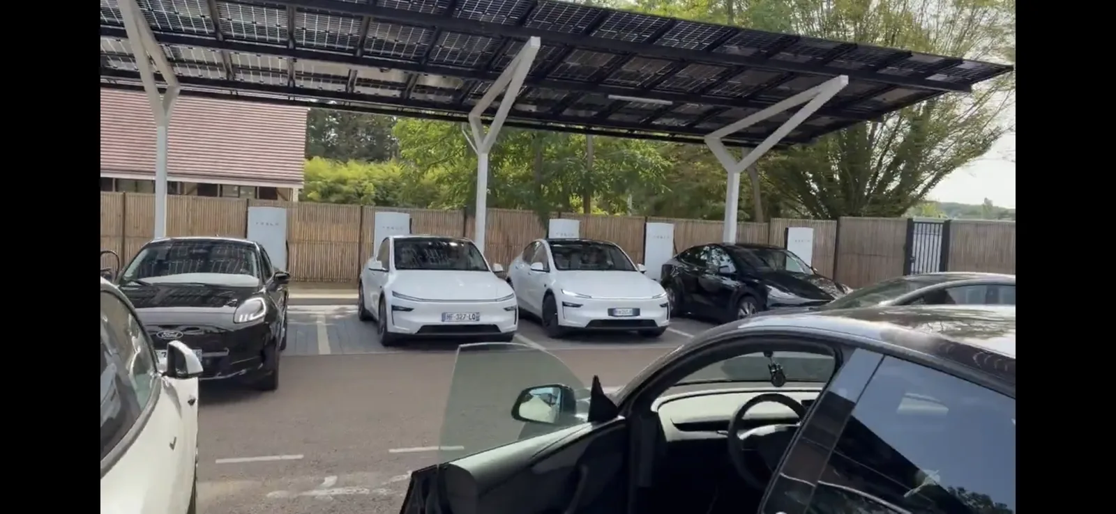 Teslas charging at a Supercharger under a solar canopy